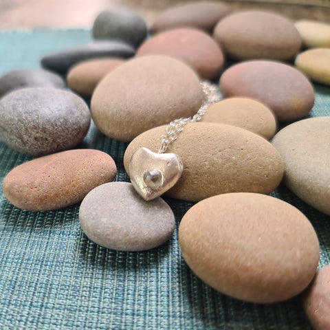 Heart-shaped pendant necklace on a bed of stones